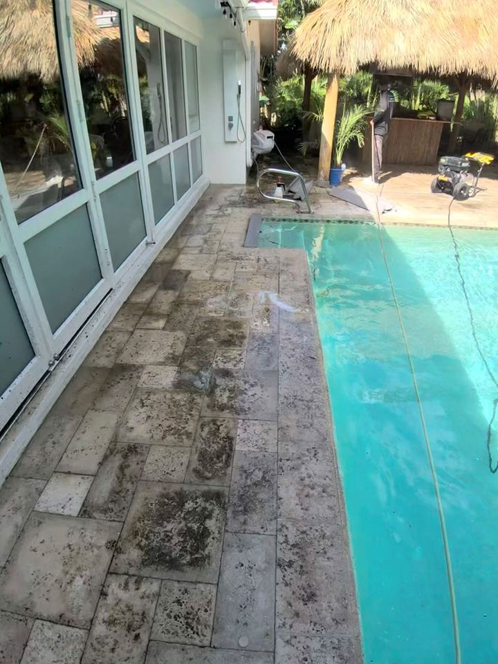 Stone pool deck next to the house covered in dark dirt and mildew before pressure washing